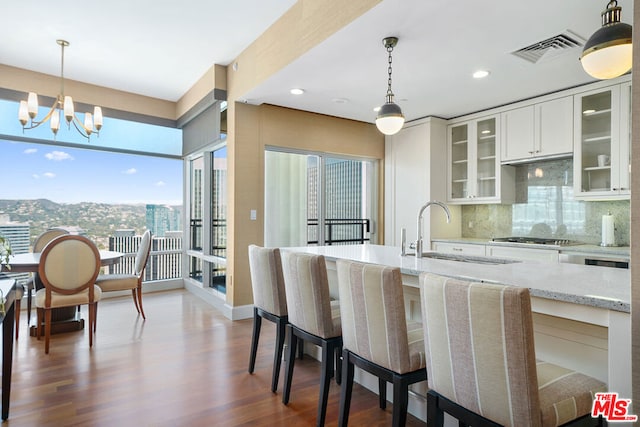 kitchen with decorative backsplash, sink, white cabinetry, light stone countertops, and a chandelier