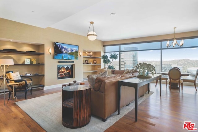 living room with built in features, a chandelier, and hardwood / wood-style floors