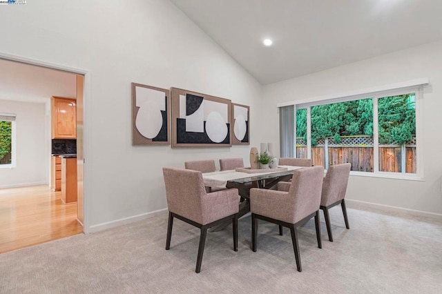 carpeted dining area with high vaulted ceiling