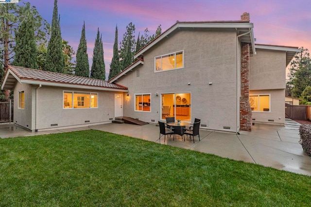 back house at dusk with a yard and a patio area