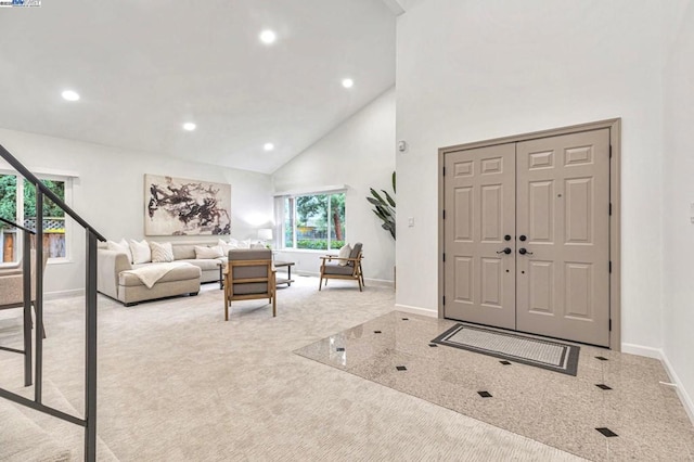 carpeted entrance foyer with high vaulted ceiling