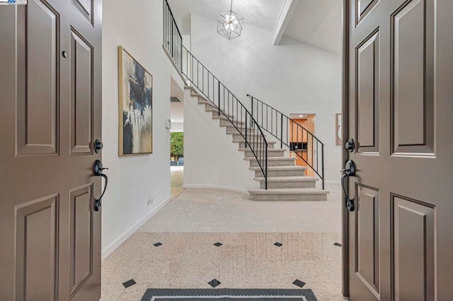 carpeted foyer entrance featuring an inviting chandelier and a high ceiling