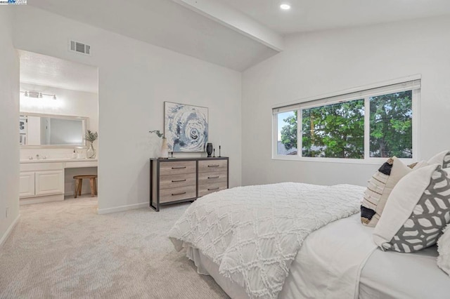 bedroom with light carpet, ensuite bath, and lofted ceiling with beams