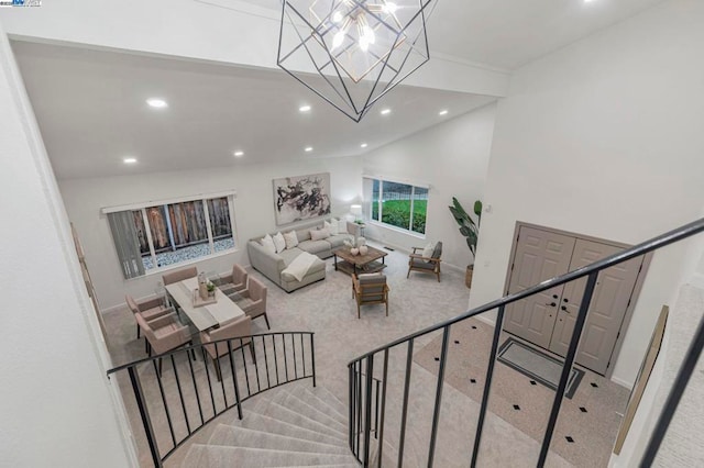 carpeted living room featuring high vaulted ceiling and a chandelier