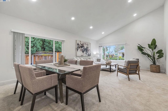 dining area with light colored carpet and high vaulted ceiling