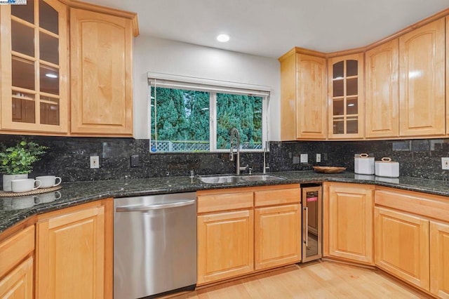 kitchen featuring light brown cabinetry, sink, dark stone countertops, stainless steel dishwasher, and decorative backsplash