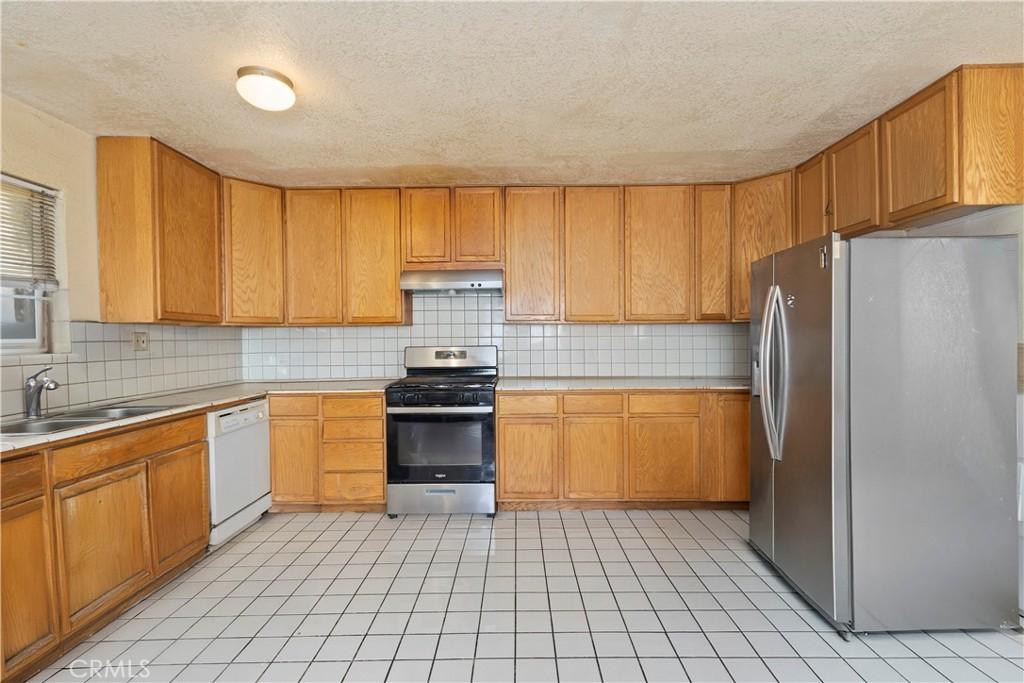 kitchen with a textured ceiling, stainless steel appliances, and sink