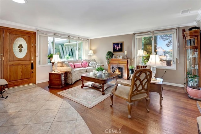 living room featuring light wood-type flooring, crown molding, and a fireplace