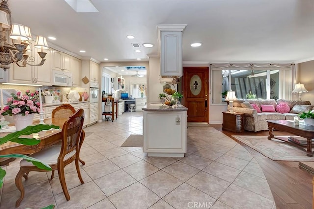 kitchen featuring crown molding, light tile patterned floors, kitchen peninsula, and white appliances