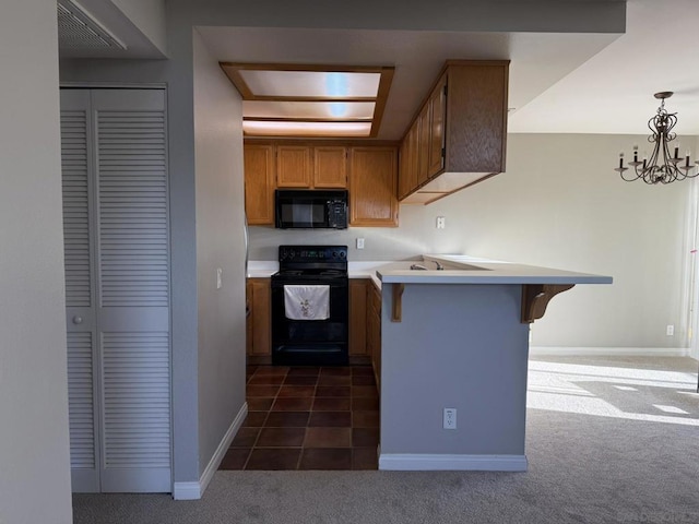 kitchen with black appliances, a kitchen bar, decorative light fixtures, kitchen peninsula, and dark carpet