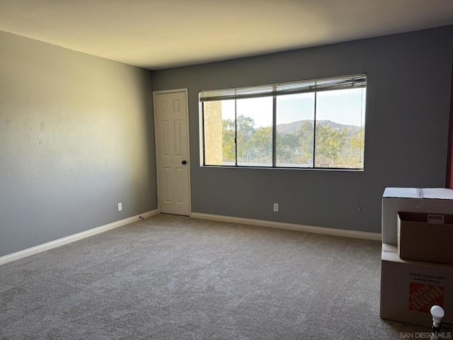 empty room with a mountain view and carpet flooring