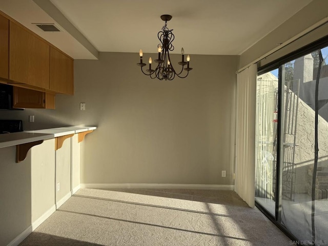 kitchen featuring a breakfast bar area, decorative light fixtures, carpet, and a notable chandelier