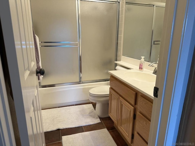 full bathroom with combined bath / shower with glass door, vanity, and toilet