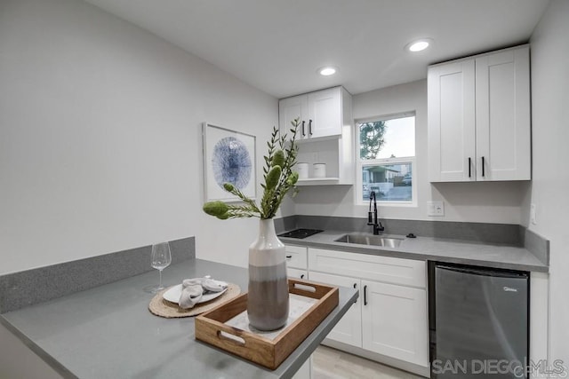 kitchen with fridge, white cabinetry, and sink