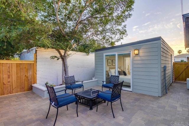 patio terrace at dusk featuring an outbuilding and an outdoor fire pit