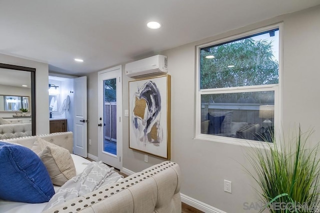 bedroom featuring an AC wall unit, connected bathroom, and hardwood / wood-style flooring