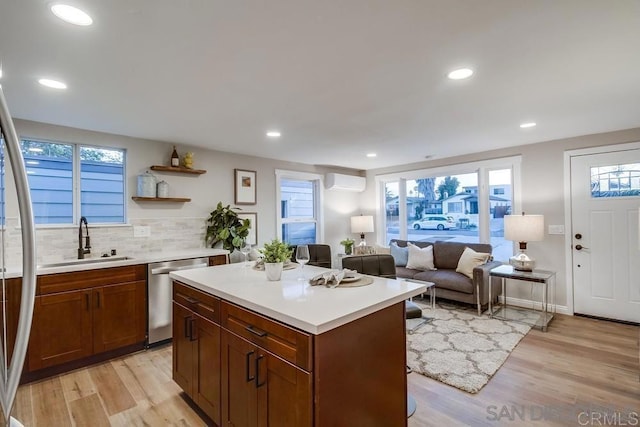 kitchen featuring dishwasher, light hardwood / wood-style floors, a center island, sink, and a wall mounted air conditioner