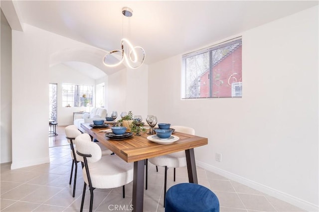 tiled dining room with vaulted ceiling and a chandelier