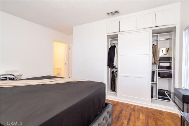 bedroom with dark hardwood / wood-style floors and a closet