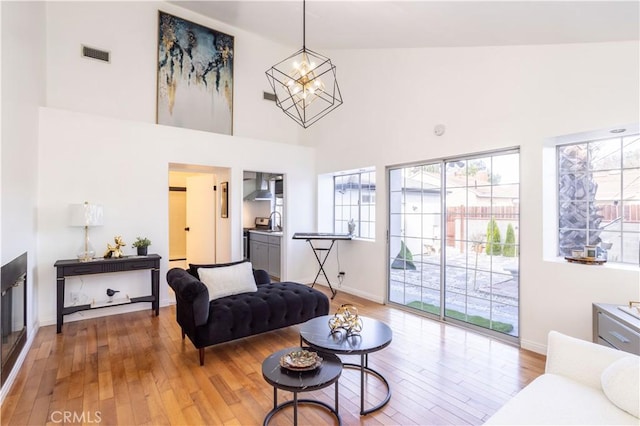 living room featuring hardwood / wood-style flooring, a notable chandelier, and a towering ceiling