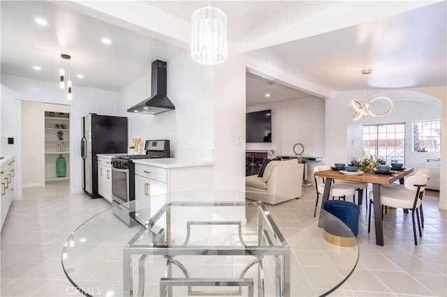 kitchen featuring hanging light fixtures, white cabinets, wall chimney exhaust hood, and stainless steel appliances