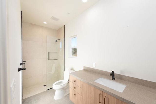 bathroom featuring tiled shower, vanity, and toilet