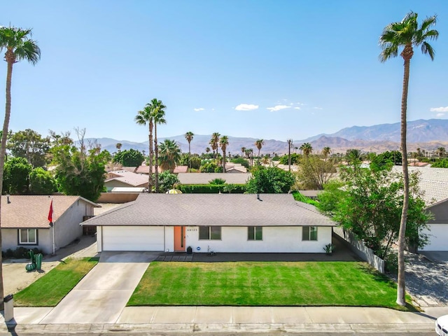 single story home with a garage, a mountain view, and a front yard