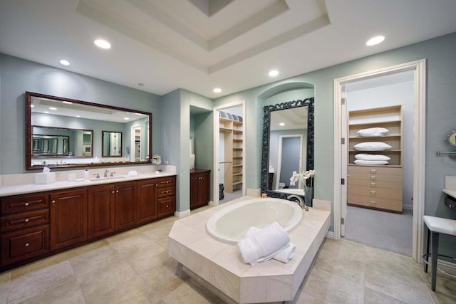 bathroom featuring vanity, tiled bath, and a raised ceiling