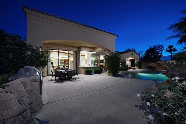 patio at night featuring area for grilling