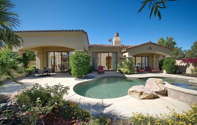 back of house with a patio and a pool with hot tub