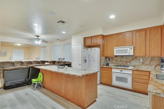 kitchen featuring white appliances, a kitchen island, tasteful backsplash, ceiling fan, and light hardwood / wood-style flooring