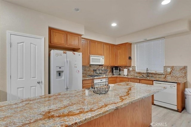 kitchen with tasteful backsplash, light hardwood / wood-style floors, sink, white appliances, and light stone countertops