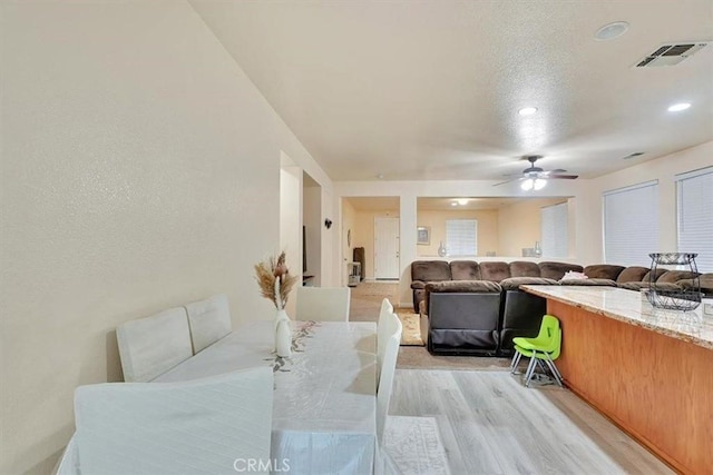 dining area with ceiling fan, a textured ceiling, and light hardwood / wood-style floors