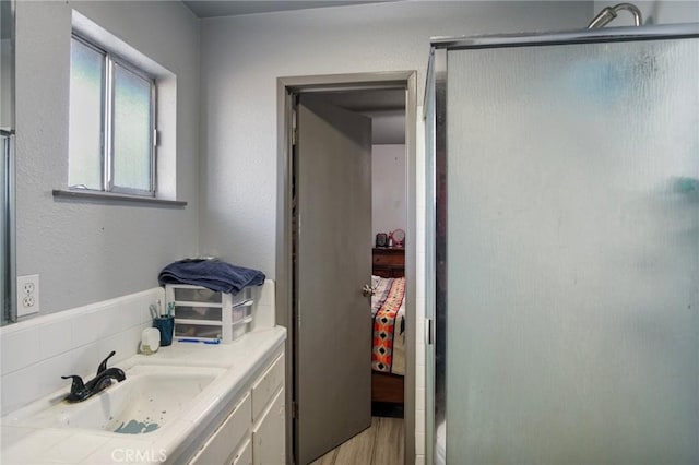 bathroom featuring vanity, wood-type flooring, and a shower with door