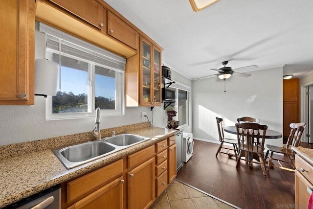 kitchen with sink, light stone counters, light tile patterned flooring, washer / dryer, and stainless steel dishwasher