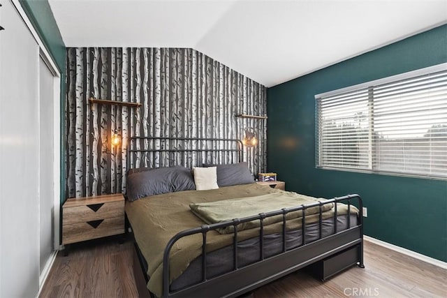 bedroom featuring vaulted ceiling, a closet, and wood-type flooring