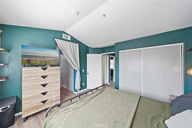 bedroom featuring a closet, lofted ceiling, and wood-type flooring