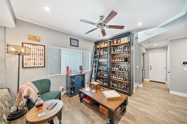 living area with light hardwood / wood-style floors, ornamental molding, and ceiling fan with notable chandelier