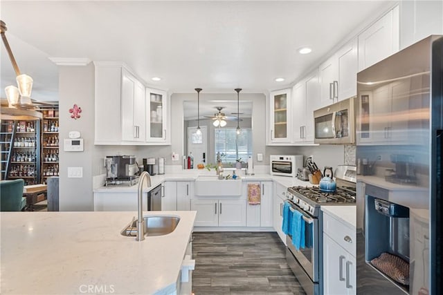 kitchen featuring appliances with stainless steel finishes, white cabinets, decorative light fixtures, and sink