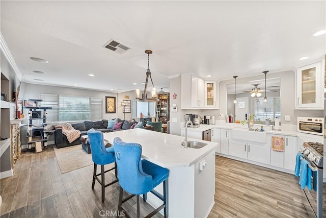 kitchen featuring a kitchen bar, stainless steel range with gas cooktop, hanging light fixtures, and sink