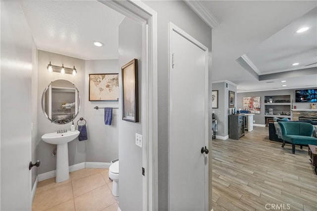 bathroom featuring toilet, built in shelves, a fireplace, and crown molding