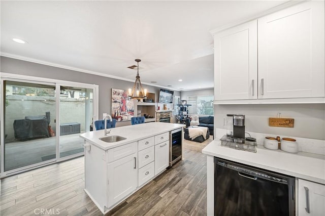 kitchen featuring decorative light fixtures, white cabinets, sink, and black dishwasher