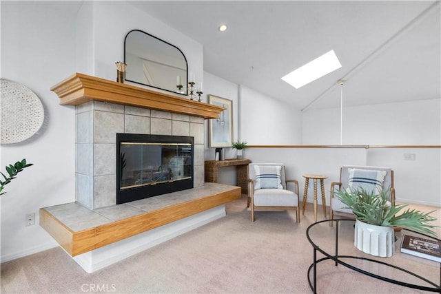 carpeted living room with a fireplace and lofted ceiling with skylight