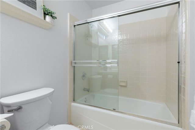 bathroom with bath / shower combo with glass door and toilet