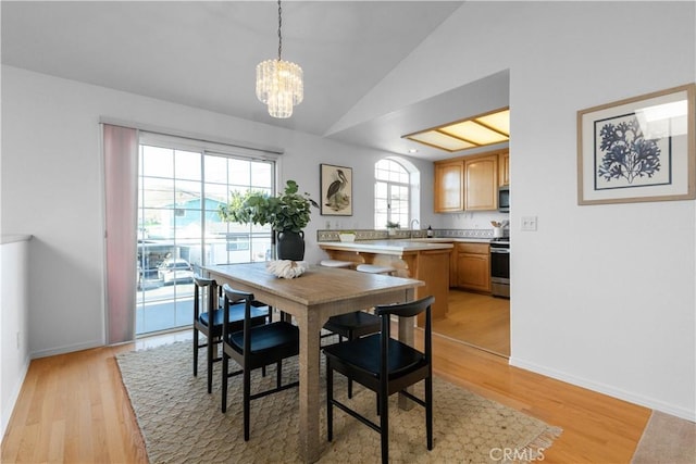 dining space with lofted ceiling, a chandelier, and light hardwood / wood-style floors