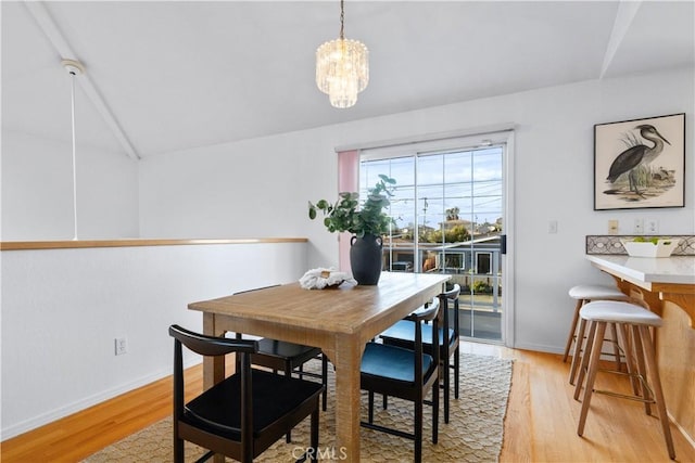 dining room with vaulted ceiling, a chandelier, and light hardwood / wood-style floors