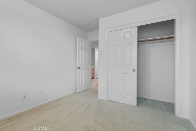 unfurnished bedroom featuring light colored carpet and a closet