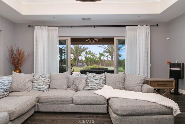 living room with ceiling fan, wood-type flooring, and a tray ceiling