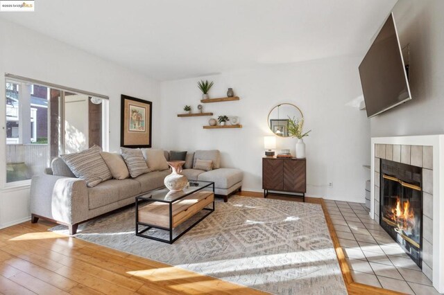 living room featuring a tile fireplace and light wood-type flooring