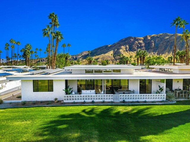 rear view of house featuring a mountain view and a yard